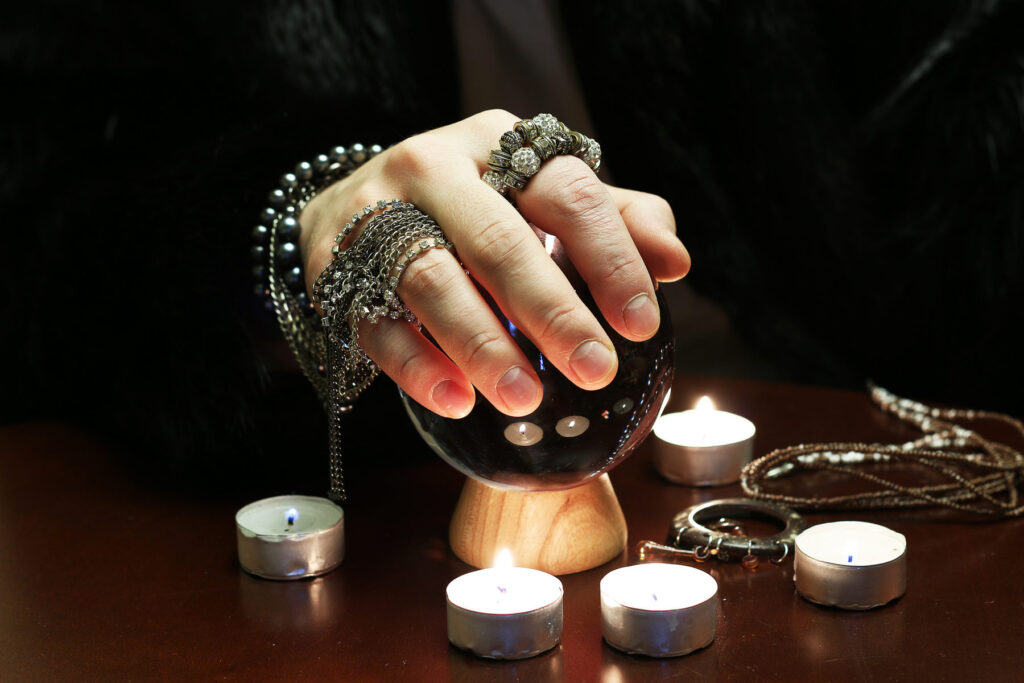 Hand with rings held over a crystal ball